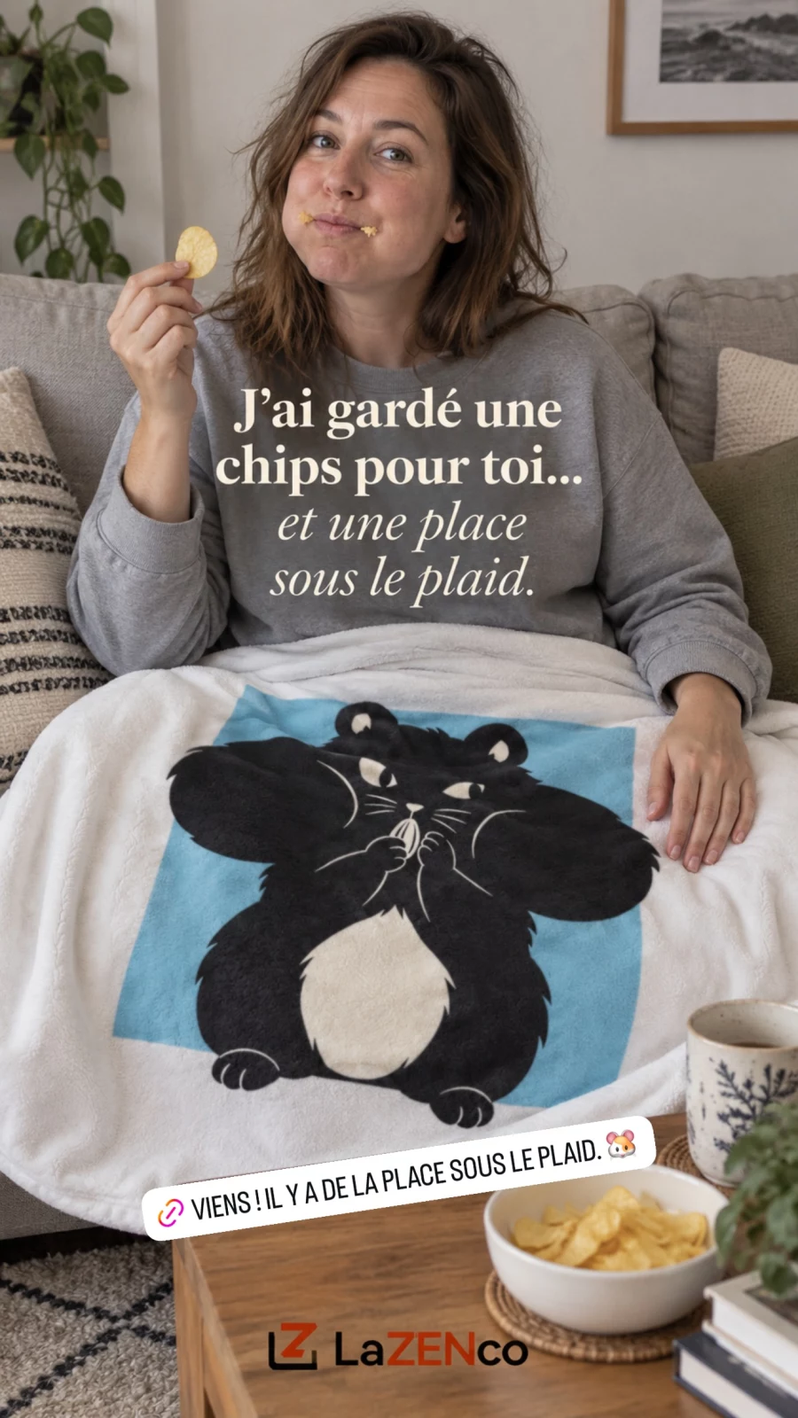 Une femme sur un canapé tient une chips, les joues pleines, sous un plaid blanc illustré du hamster aux joues pleines sur fond bleu glacier.