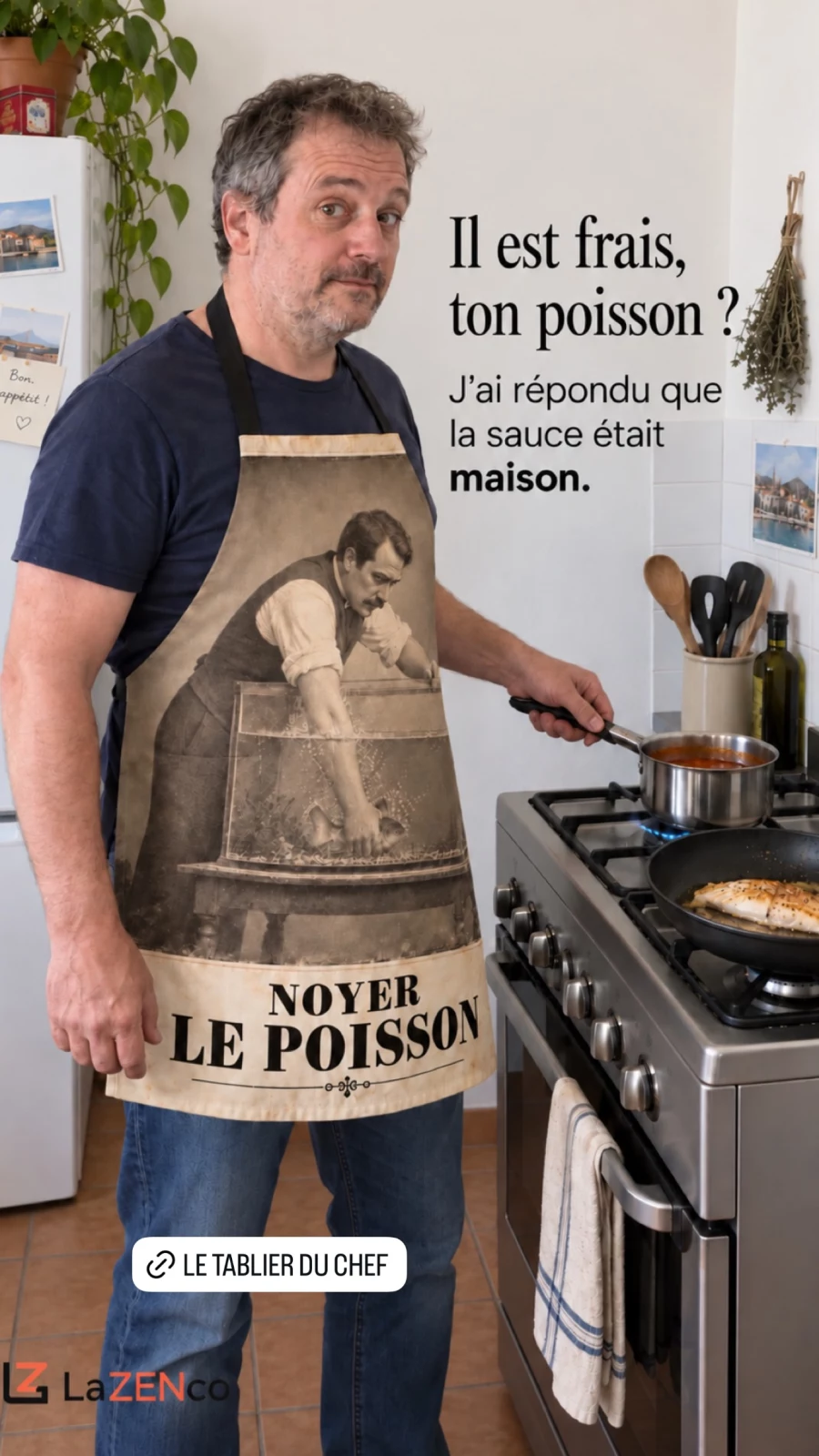 Un homme dans sa cuisine porte le tablier Noyer le poisson et tient une casserole de sauce près du poisson en cuisson.