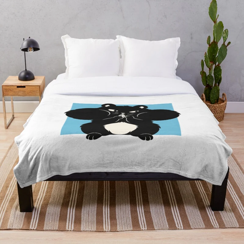 Plaid LaZENco posé sur un lit, avec un hamster noir aux joues pleines sur un carré bleu